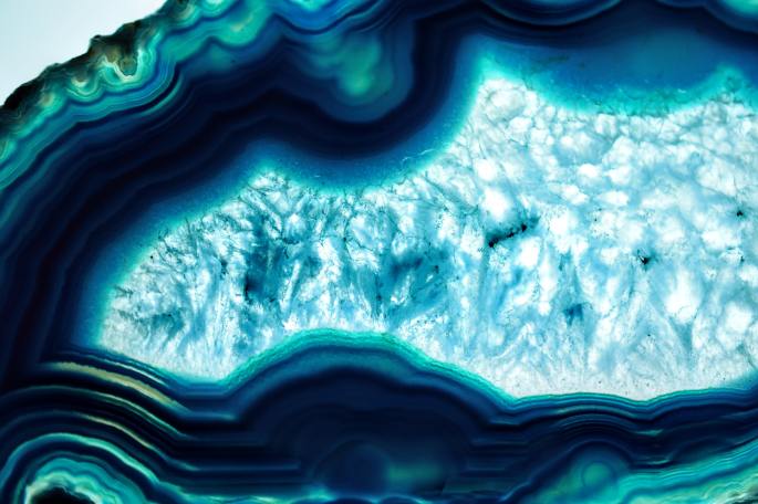A close up image of a geode slice, with teal and dark blue colors.